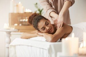 Tender beautiful african girl smiling enjoying massage with closed eyes in spa resort.